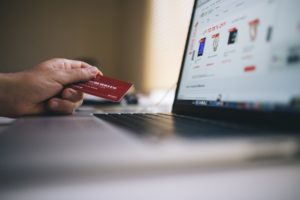 'Hand of a person facing holiday debt holding credit card and looking at their balance on a computer screen