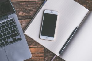 Preparing to sort finances with phone, notepad and laptop